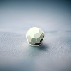 a round object sitting on top of a gray surface with drops of water around it