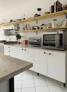 a kitchen filled with lots of counter top space and white cabinets next to a wall mounted microwave oven