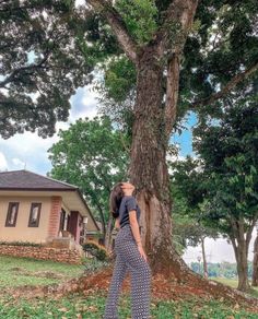 a woman standing in front of a large tree