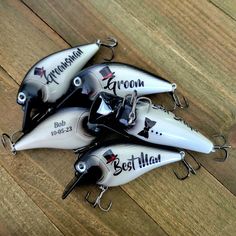 four fishing lures with personalized names on them sitting on a wooden surface,