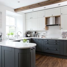 a kitchen with white and gray cabinets, wood floors and wooden beams in the ceiling