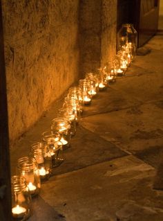 many lit candles are lined up on the ground