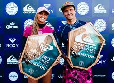 two people standing next to each other holding trophies