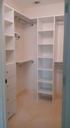 an empty walk in closet with white shelving