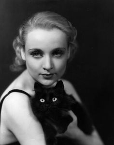 an old black and white photo of a woman holding a cat in her arms with eyes wide open