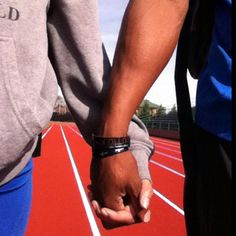 two people holding hands while standing on a track