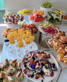 a table filled with lots of different types of food on plates and glasses next to each other