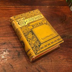 an old yellow book sitting on top of a wooden table