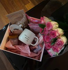 pink roses and coffee mug sitting on top of a table next to a bouquet of flowers