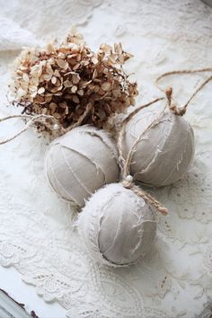 three ornaments are sitting on a lace doily with twine and burlap