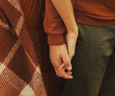 two people holding hands while standing next to each other in front of a checkered blanket