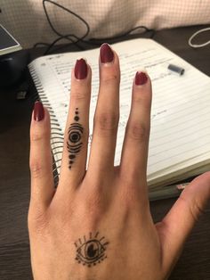 a woman's hand with two finger tattoos and an eye tattoo on her left thumb