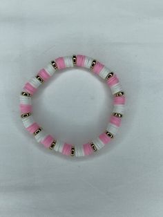 a pink and white beaded bracelet with bells on it's end is shown