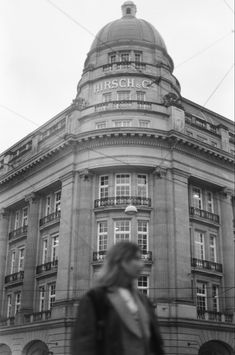 black and white photograph of a woman walking in front of a building