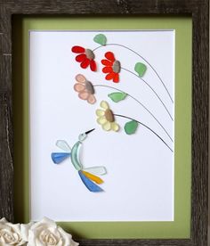 paper flowers and leaves are arranged in a shadow box frame on a table next to a white rose