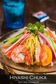 a plate with shrimp, carrots and celery on it next to a glass of water