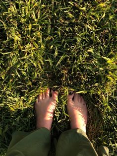 someone is standing in the grass with their feet on the ground, looking down at them