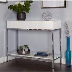 a white console table with some plants on it and a blue vase next to it