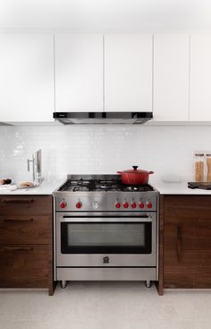 a stove top oven sitting inside of a kitchen next to wooden cabinets and counter tops