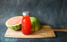 a bottle of watermelon juice sitting on top of a cutting board