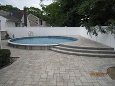 a backyard with a pool and steps leading up to the side of the house that has a white fence around it