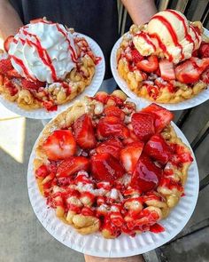 three waffles with strawberries and ice cream on them are sitting on paper plates