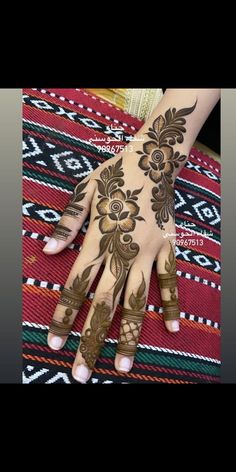 a woman's hand with henna tattoos on it and her hands painted brown