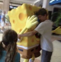 a man is hugging a giant stuffed spongebob