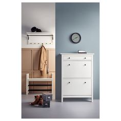 a white dresser sitting next to a wall with a clock on it's side