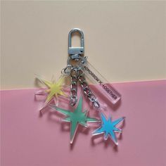 three star shaped key chains on a pink surface