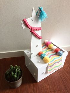 a toy horse sitting on top of a white box next to a potted cactus