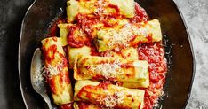 some ravioli with sauce and parmesan cheese in a black bowl on a table