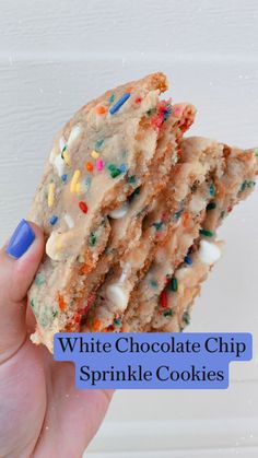 a hand holding a cookie with sprinkles and frosting