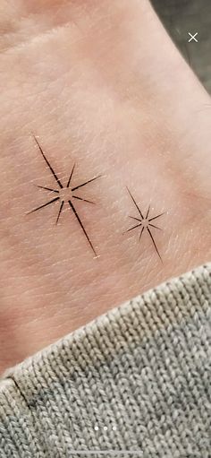 a small star tattoo on the left side of the wrist, with three smaller stars above it