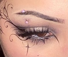 a woman's eye with some piercings on her forehead and eyelashes in front of her face