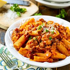 pasta with meat sauce and parmesan cheese in a white bowl on a wooden table