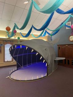 an inflatable shark tent with blue streamers hanging from the ceiling