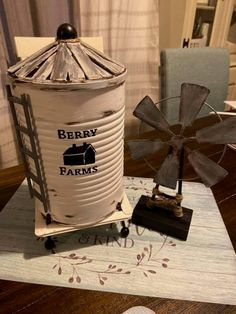 an old tin can sitting on top of a wooden table next to a small windmill