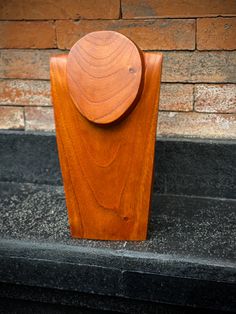 a wooden object sitting on top of a black stone floor next to a brick wall