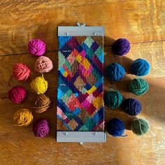 several balls of yarn sitting on top of a wooden table next to a crochet bag