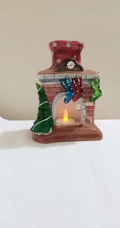 a lit candle is sitting in front of a small brick house with stockings on it