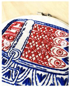 a red white and blue embroidered object sitting on top of a wooden table