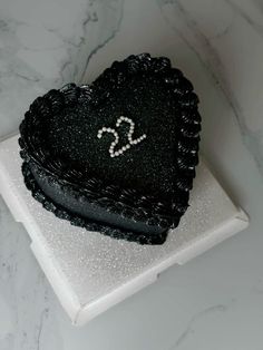 a black heart shaped cake sitting on top of a white plate with the letter s in it