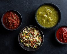 three bowls filled with different kinds of salsa next to each other on a black surface