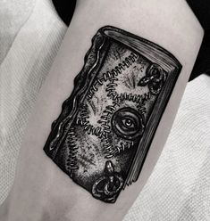 a black and white photo of a book tattoo on the left arm with eyeballs