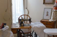 an old sewing machine sitting on top of a wooden table next to a white chair