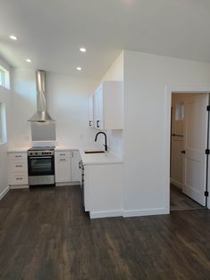 an empty kitchen with white cabinets and wood flooring in the room that is being used as a studio apartment