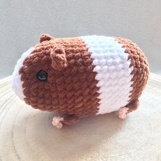 a brown and white crocheted hamster sitting on top of a wooden table