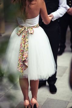 a woman in a white dress is walking down the street