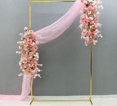 a pink and white wedding arch with flowers